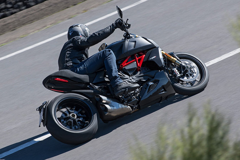 Motocyklista w czarnym kombinezonie na czarnym motocyklu marki Ducati