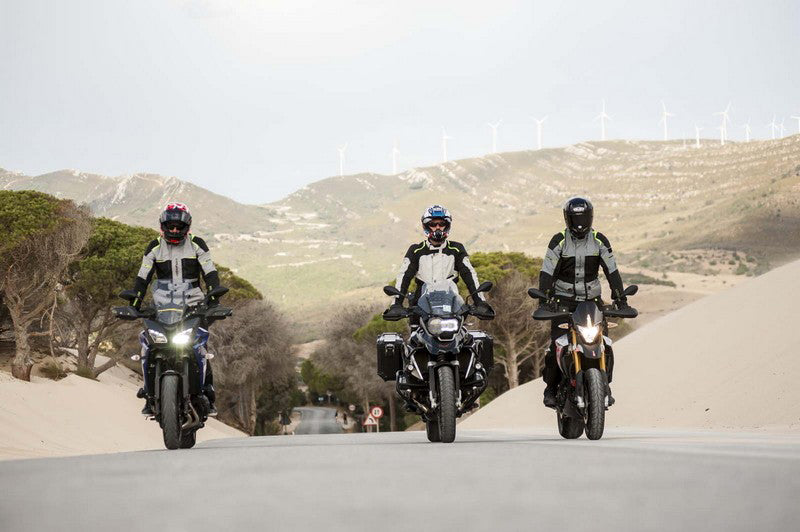 trzech motocyklistów na asfaltowej drodze obok piaszczyste pobocze 
