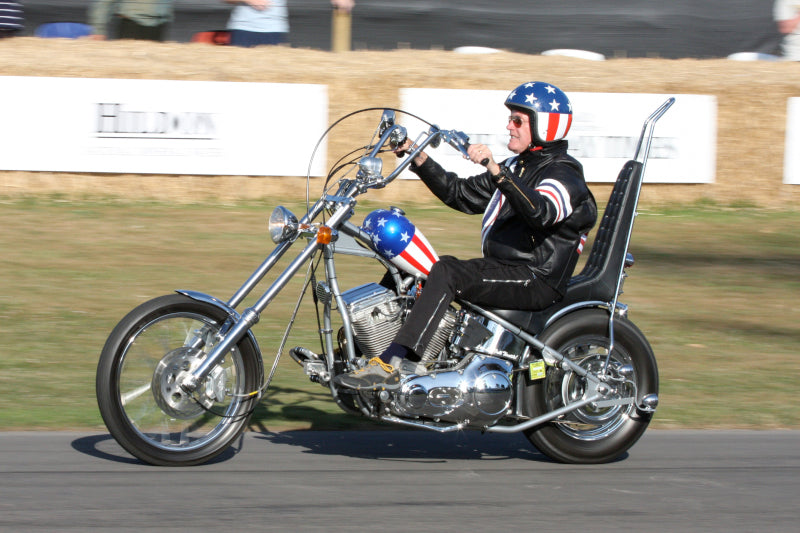 motocyklista jadący na amerykańskim motocyklu typu chopper, bak motocykla i kask motocyklisty pomalowane we wzór amerykańskiej flagi