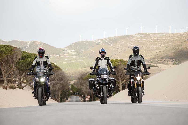 trójka motocyklistów jedzie w pięknych okolicznosciach przyrody