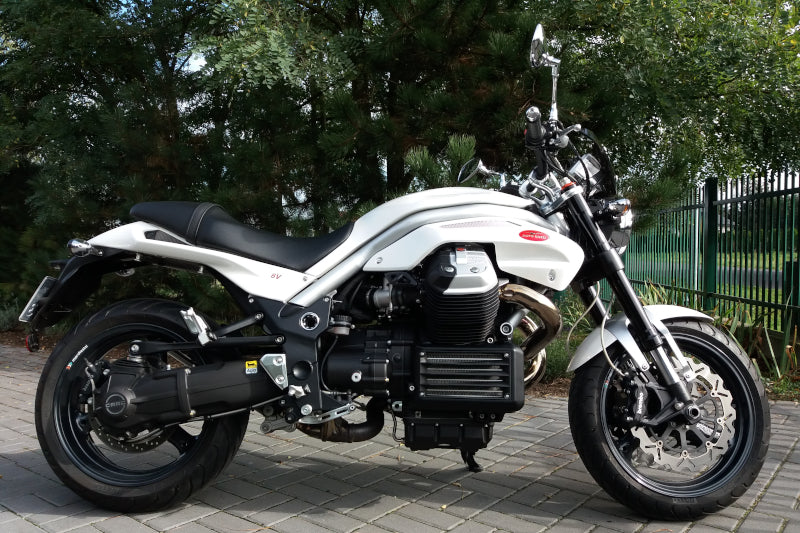 biały motocykl moto guzzi stoi na podwórku