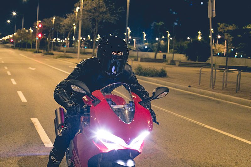 motocyklista jadący nocą po ulicach miasta w swoim pierwszym kasku motocyklowym