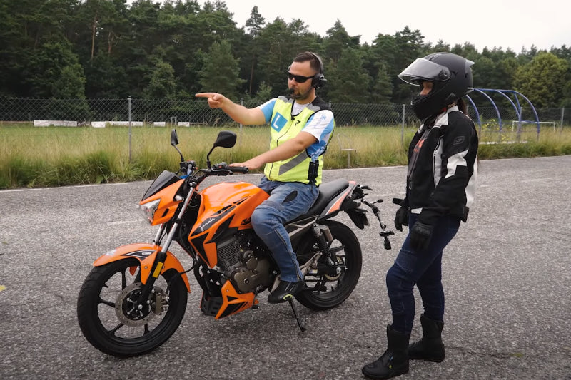 Kobieta uczy się jeździć na motocyklu pod okiem instruktora