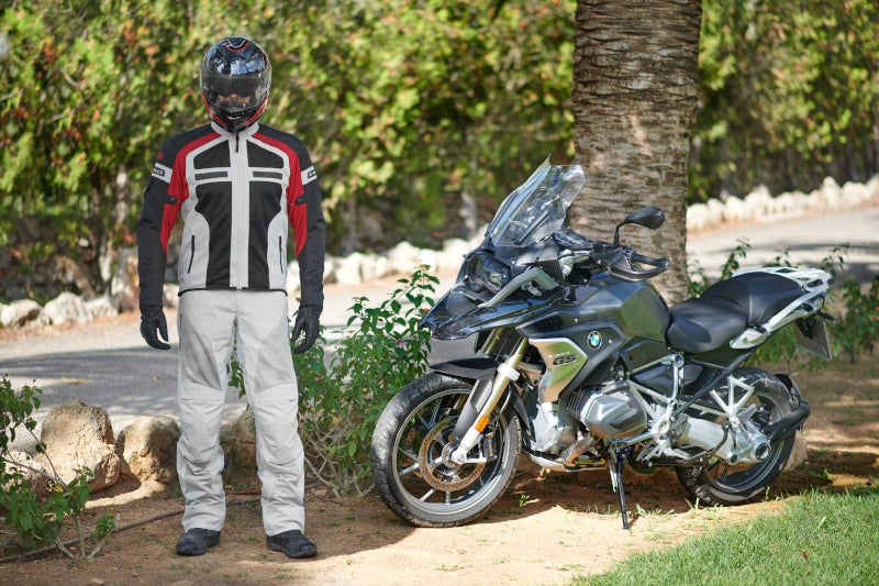 mężczyzna w stroju motocyklowym stoi w cieniu na trawie