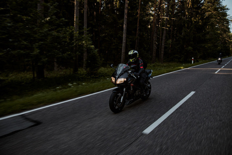 motocyklistka jedzie w lesie po szosie na motocyklu sporotwo-turystycznym suzuki sv650