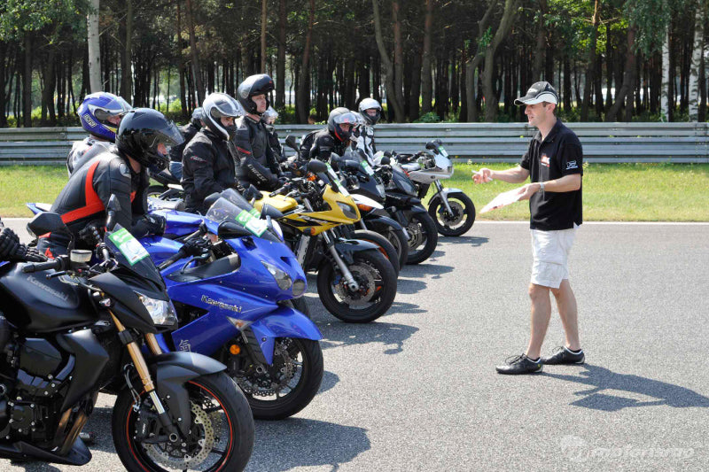 szkolenie motocyklowe, instruktor stoi na torze przed grupą motocyklistów