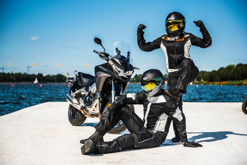 dwoje motocyklistów na końcu betonowego pomostu przy motocyklu ubrani w tekstylne kombinezony 