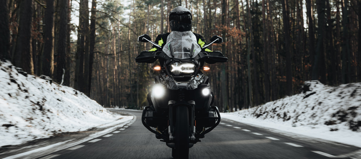 Motocyklista na motocyklu jedzie drogą w czasie zimy