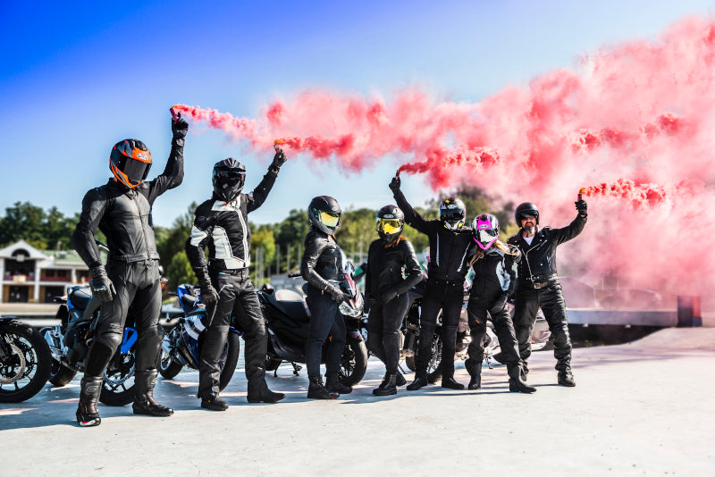 grupa motocyklistów stoi przy swoich maszynach i palą race