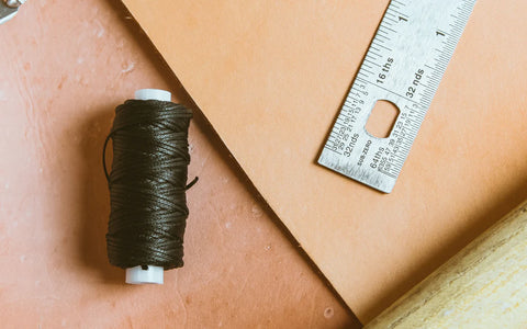 dark green yarn and part of a ruler on top of leather materials