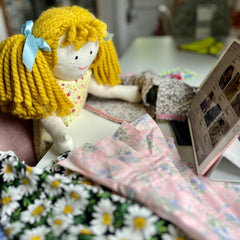 An Alice doll looking at sewing patterns.