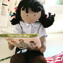 An Olivia doll reading a magazine.