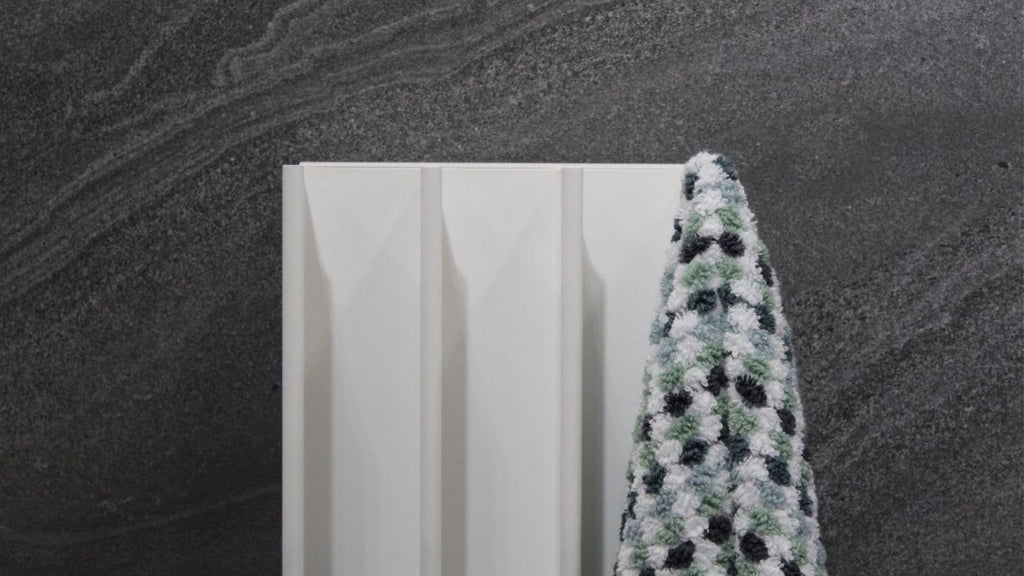 White heated towel rail mounted on slate bathroom tiles