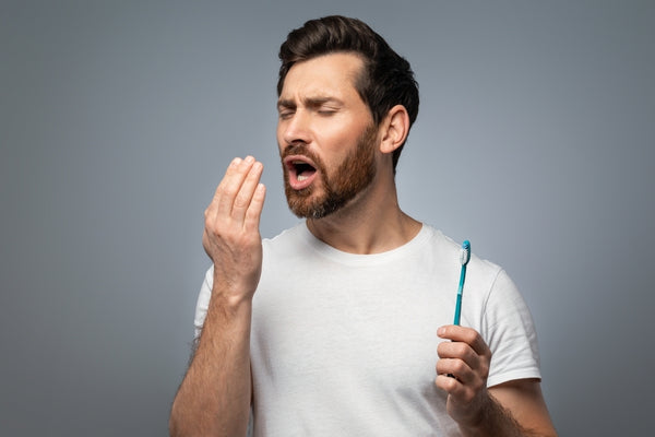 A man checks whether he has fresh breath after brushing his teeth