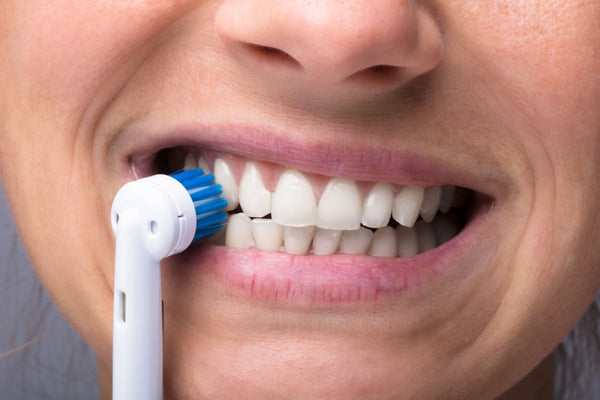 Close-up of woman using an electric toothbrush