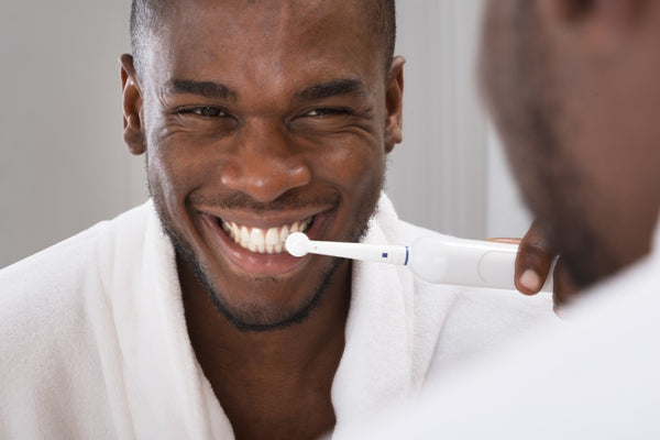Man smiles while using an electric toothbrush