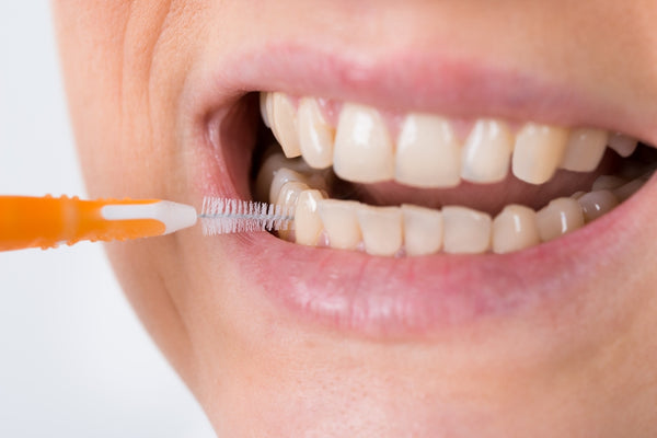 Woman cleans between her teeth using an interdental brush