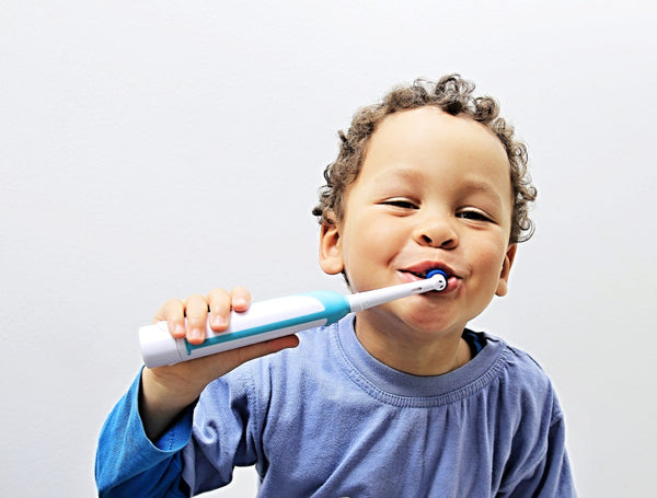 Young boy brushes his teeth with an electric toothbrush