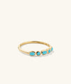 Bezel Turquoise Half Eternity Ring: a handcrafted 14k yellow gold ring adorned with vibrant turquoise gemstones, perfect for adding a beachy touch to your look.