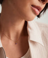 Close-up of a woman’s neck wearing a 14k gold handcrafted Birthstone Charm necklace, highlighting the intricate design and elegance of the jewelry.