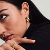 Woman wearing Gemstone Mini Studs, showcasing 14k gold handcrafted earrings with vibrant tones. Her hand rests on her chin, highlighting the elegant jewelry.