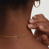 Curb Chain Extender: Close-up of a gold chain on a woman's neck, with a hand gently touching a bracelet, showcasing the extender's added length.