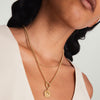 Woman wearing the Energy: Sun Coin Charm Pendant, a handcrafted 14k gold necklace inspired by the sun's power, shown as a close-up.