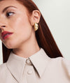 Woman wearing Mega Dôme Earrings, looking to the side. Focus on her lips, neck, and the bold earrings from the Dôme collection.