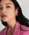 Woman with long black hair wearing Pressed Flower Two-Tone Large Stud Earrings in sterling silver and 18k gold vermeil, paired with a pink jacket.