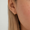 Close-up of a woman's ear wearing a Single Easy Huggie Hoop, a handcrafted 14k gold earring with a clicker closure for comfort.