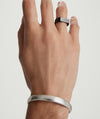 Hand wearing a Bold Cuff bracelet and a ring, showcasing the simple yet bold silhouette of the fashion accessory.