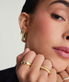 Close-up of a woman wearing Ribbed Oversized Hoops, showcasing the intricate design and fashionable appeal of the gold earrings.