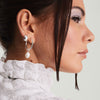 Woman wearing white shirt and earrings, showcasing Organic Pearl Hoop Charms. Close-up highlights silver ring, eye, lips, and nose for detail.