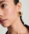 Woman wearing Patra Oversized Hoops, a pair of lightweight gold earrings designed for comfort. Close-up of earring and ear visible.