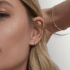 Close-up of a woman's ear wearing a Serpentine Chain Bracelet with flat, braided links.