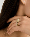 Hand adorned with gold rings, including the versatile Stacker Ring, featuring a textured band, paired with a matching gold bar earring and delicate chain necklace.