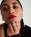 Woman with red lipstick and black hair holding her chin, showcasing the Patra Chunky Ring on her finger, highlighting bold, elegant fashion accessories.