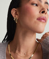 Woman wearing Chunky Large U Hoops with clicker closure, paired with a necklace and earrings, showcasing the fashion accessory's design and comfort.