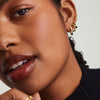 Close-up of a woman wearing Pleated Huggie U Hoop earrings, handcrafted in 14k gold, highlighting elegant design and detailed craftsmanship.