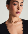 Woman wearing a Mini Heart Pavé Diamond Necklace, featuring a delicate heart-shaped pendant encrusted with pavé diamonds, paired with other gold necklaces.