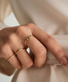 Hand with emerald and diamond wishbone ring in 14k gold, featuring emerald gemstones and responsibly sourced diamonds.