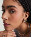 Woman wearing Chunky Large U Hoops with clicker closure, showcasing their pillowy design and secure fit. Hand under chin, highlighting earrings prominently.