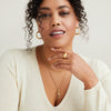 Woman with curly hair wearing a white sweater, showcasing the Bold Letter Pendant Necklace in 18k gold vermeil with an accordion pattern on a 20-22 inch chain.