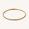 Thin Flexi Bangle: a handcrafted, hollow 14k gold bangle, minimal and flexible, displayed on a white surface. Ideal for everyday wear.