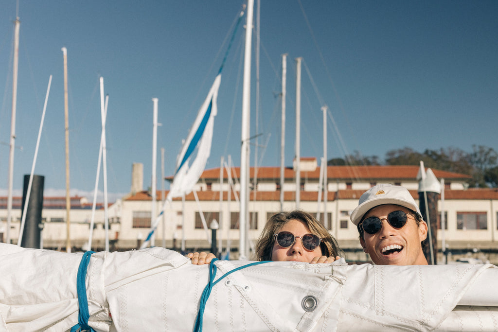 Two people peeking over a sail on a sailboat