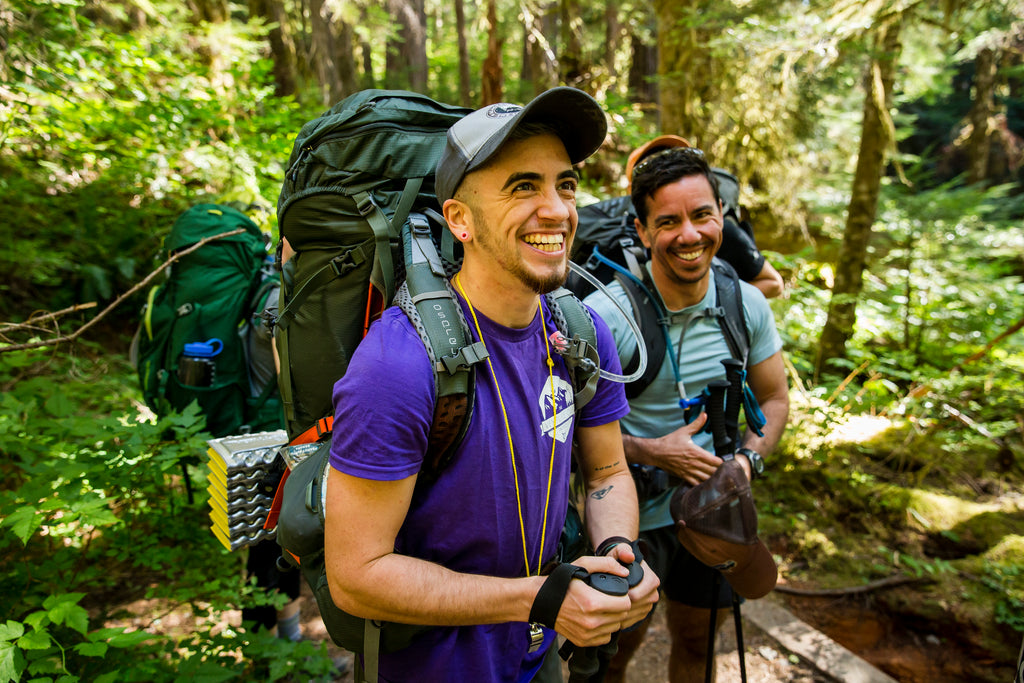 Two people all smiles on their forest backpacking trip