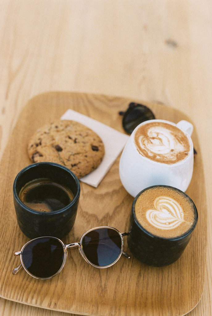 An array of pastries and coffees on a wood cutting board