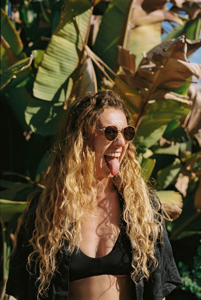 Person with long curly hair sticking out their tongue for the camera