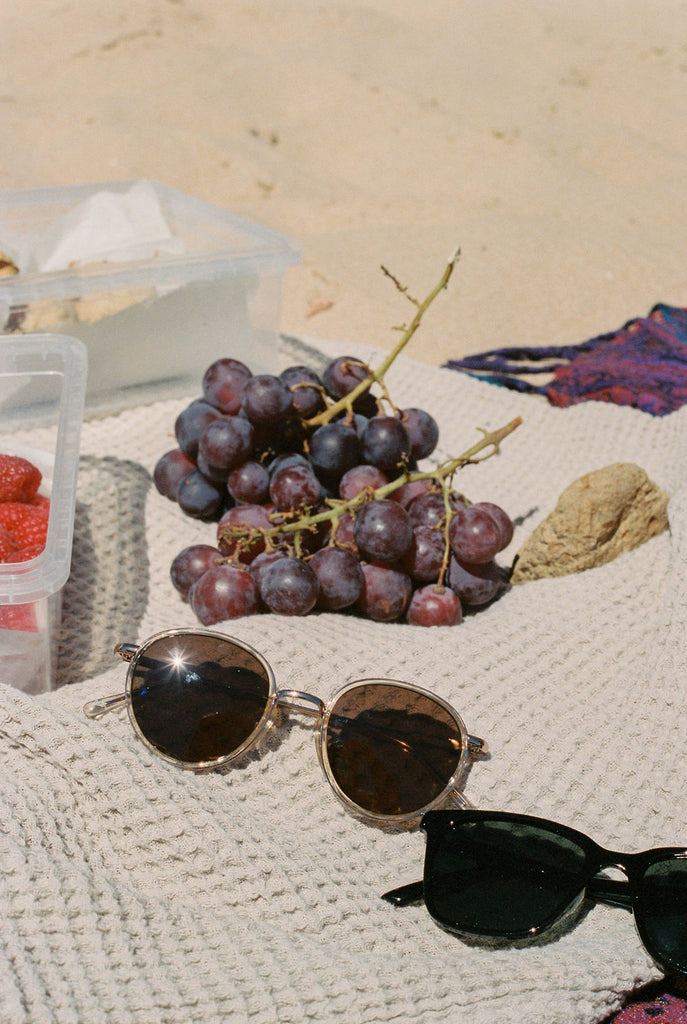 Fruit and sunglasses on a beach blanket