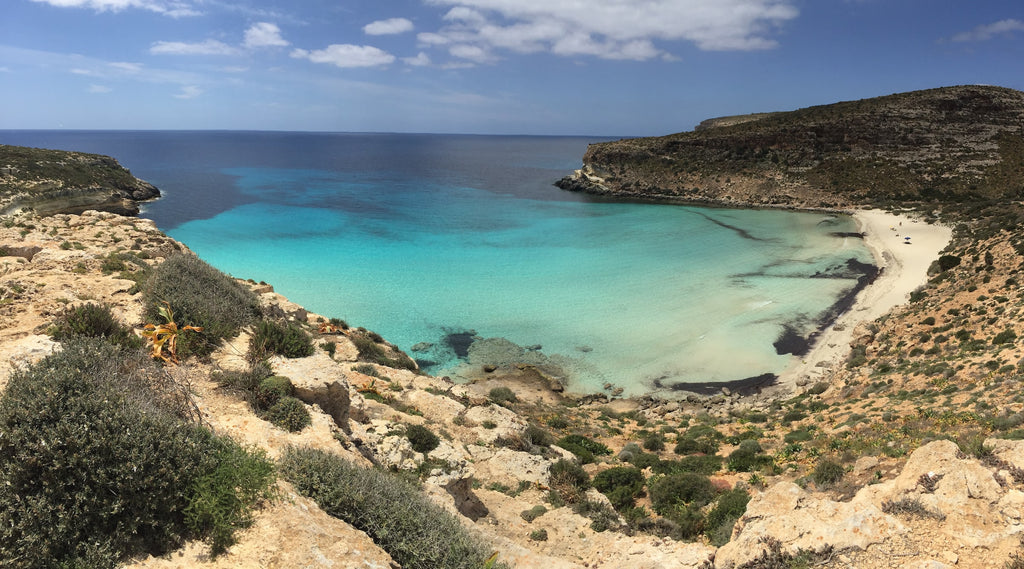 small, bright blue bay on a rugged coast